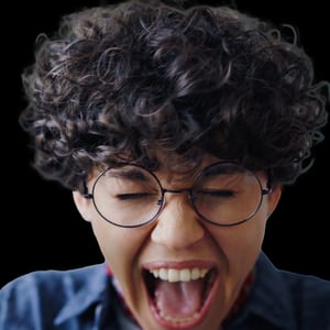 A young woman with curly hair and glasses screams in frustration