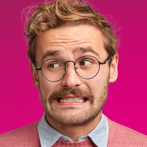 A man with glasses looks leftward in embarrassment