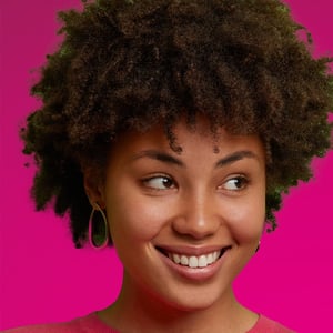 A young, confident Black woman looks to the right and smiles